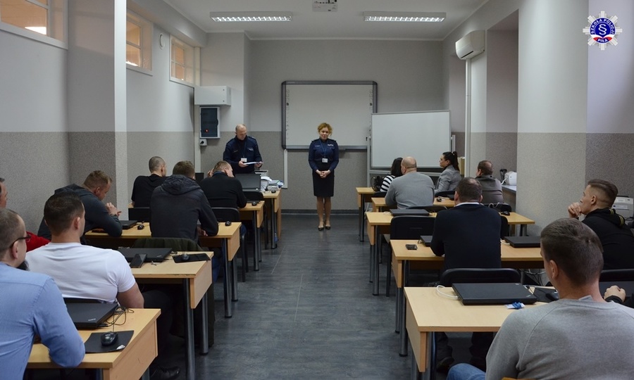 Sala wykładowa, w której uczestnicy kursu siedzą i słuchają przemówienia stojącej na środku kierownik Zakładu podsumowującej szkolenie.