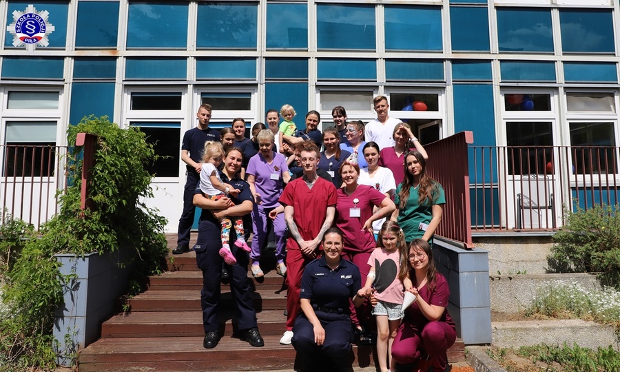 Zdjęcie grupowe przedstawicielami szkolnego samorządu z personelem Szpitala Specjalistycznego w Pile i dziećmi - podopiecznymi szpitala. W tle budynek szpitala.