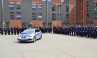 Umundurowani policjanci stojący w szyku na placu apelowym Szkoły policji w Pile. Po środku stoi oznakowany radiowóz.