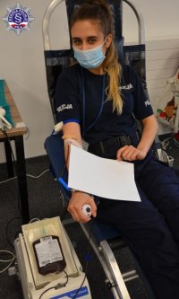 Umundurowana policjantka siedzi na fotelu z podłączoną aparaturą i oddaje krew.