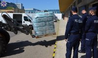 Słuchacze Szkoły Policji w Pile w maseczkach na twarzy podczas załadunku palety z wodą butelkowaną.
