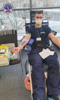 Mężczyzna w policyjnym mundurze, siedząc na fotelu oddaje krew.