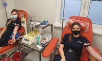 Dwie policjantki w maseczkach na twarzach, siedzą na fotelach i pobierana im jest krew.