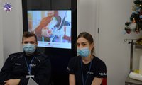 Dwóch policjantów w maseczkach, w tle widać pokaz multimedialny.