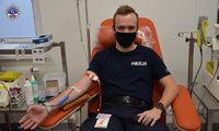 Policjant siedzący podczas oddawania krwi.