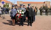 Delegacja umundurowanych policjantów oraz przedstawiciela Straży Pożarnej podczas składania okolicznościowego wieńca pod pomnikiem.