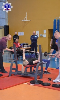 Kobieta w trakcie wyciskania sztangi w pozycji leżącej.