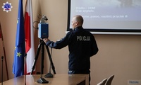 Podom. Artur Pinkowski ze Szkoły Policji w Pile przy skanerze 3D. Obok flaga Polski i flaga Unii Europejskiej