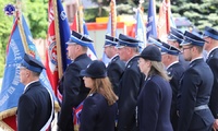 Poczty sztandarowe straży pożarnej stoją na placu zwróceni frontem do zaproszonych gości.