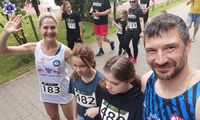 Grupa czterech osób w strojach sportowych, mężczyzna, kobieta, dwie młode dziewczyny biorąca udział w biegu.