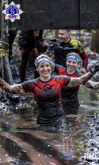 Uśmiechnięte zawodniczki przeprawiające się przez bagno.