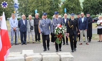 Umundurowani funkcjonariusze składający kwiaty pod pomnikiem.