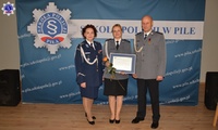 Na środku stoją trzy osoby, Komendant Szkoły Policji w Pile ze swoim Zastępcą oraz wyróżniony funkcjonariusz, w tle baner z logo Szkoły Policji w Pile