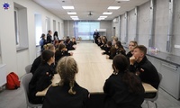 Grupa uczniów klas policyjnych siedząca przy długim stole w sali dla techników kryminalistyki.