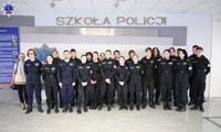 Zdjęcie grupowe uczniów szkoły średniej przed logo Szkoły Policji w Pile w budynku głównym Szkoły