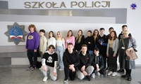 Zdjęcie grupowe uczniów szkoły podstawowej przed logo Szkoły Policji w Pile w budynku głównym Szkoły