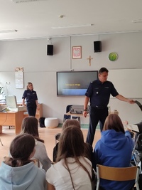 Zdjęcie kolorowe, policjant i policjantka prowadzą zajęcia i wykłady dla młodzieży i dorosłych