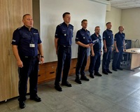 Zdjęcie kolorowe, policjanci w niebieskich mundurach kończący kurs dla techników kryminalistyki. Zastępca Komendanta Szkoły wręcza świadectwa ukończenia kursu w obecności kadry dydaktycznej Szkoły