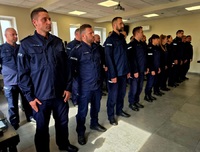 Zdjęcie kolorowe, policjanci w niebieskich mundurach kończący kurs dla techników kryminalistyki. Zastępca Komendanta Szkoły wręcza świadectwa ukończenia kursu w obecności kadry dydaktycznej Szkoły
