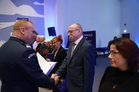Komendant Mariusz Jaworski wręcza listy gratulacyjne pracownikowi służby cywilnej.