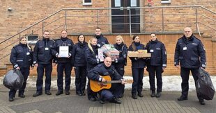 umundurowani policjanci stoją z paczkami przed wejściem do budynku szkoły