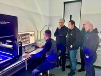 Technicy wpatrują się w ekran komputera na którym wyświetlone są w dużym przybliżeniu ślady odbitek odcisków palców