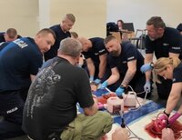 Grupa policjantów ćwiczy opatrywanie ran pod nadzorem instruktora Stop the Bleed.