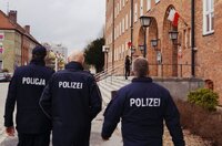 Goście w towarzystwie Komendanta Sapuna idą przed frontem budynku głównego.