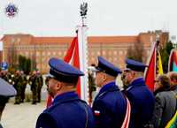 poczet sztandarowy podczas uroczystości w tle budynek Szkoły Policji w Pile
