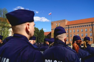 Policjanci na tle budynku Szkoły Policji w Pile.