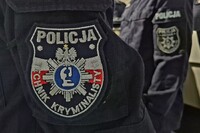 ramię policjanta z emblematem techników kryminalistyki